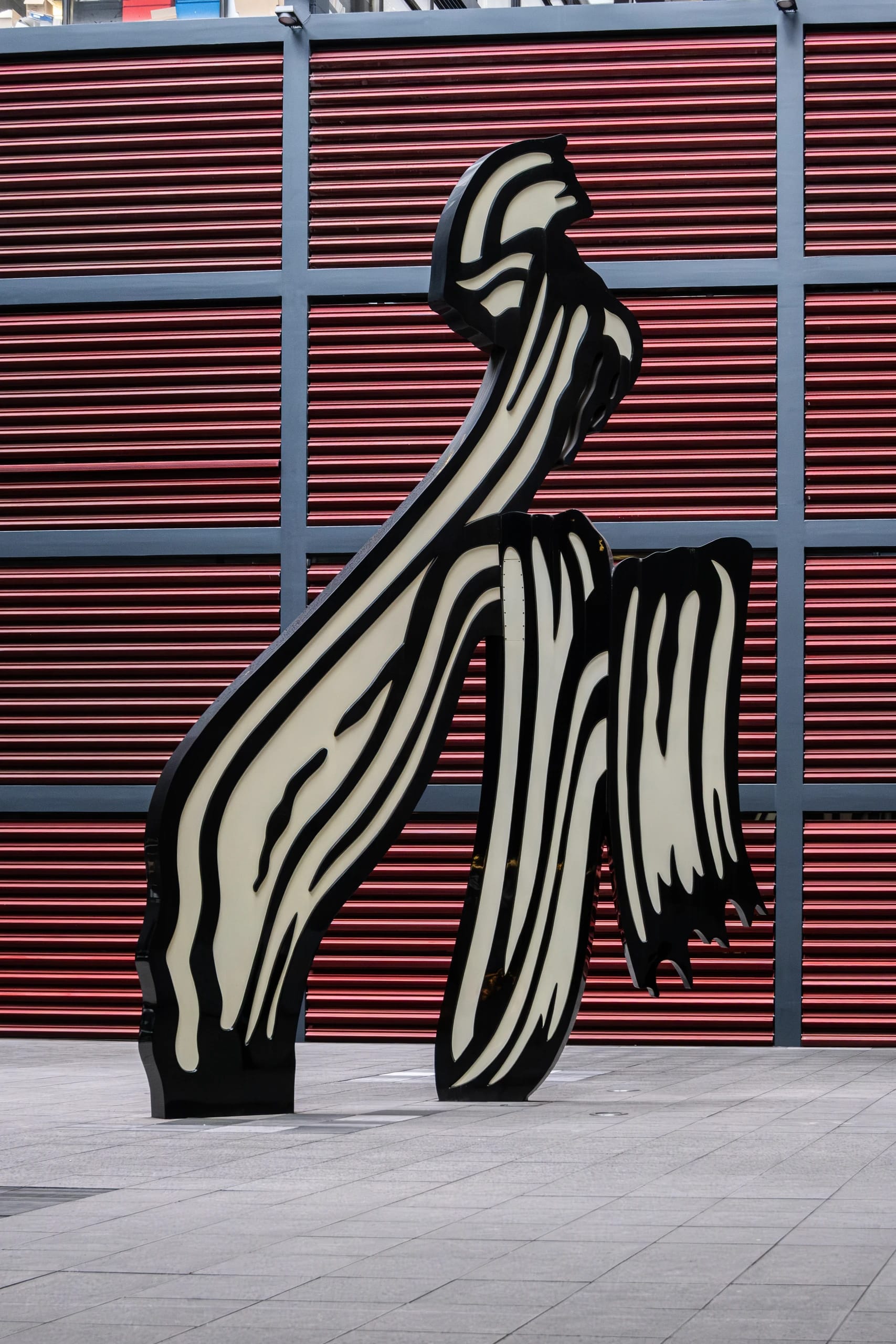Black and white sculptural forms against red horizontal slats
