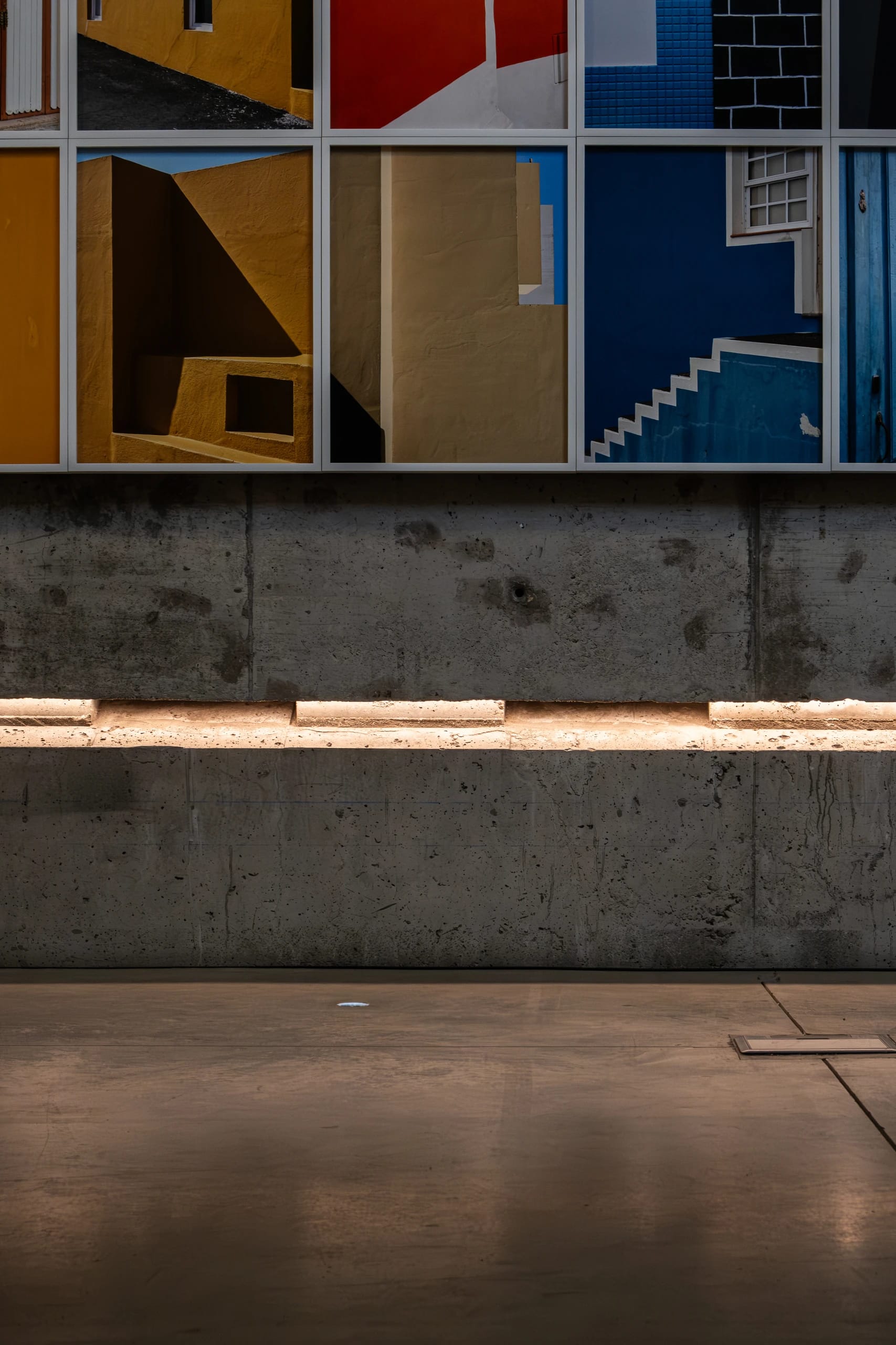 Colourful architectural photographs above an illuminated concrete wall