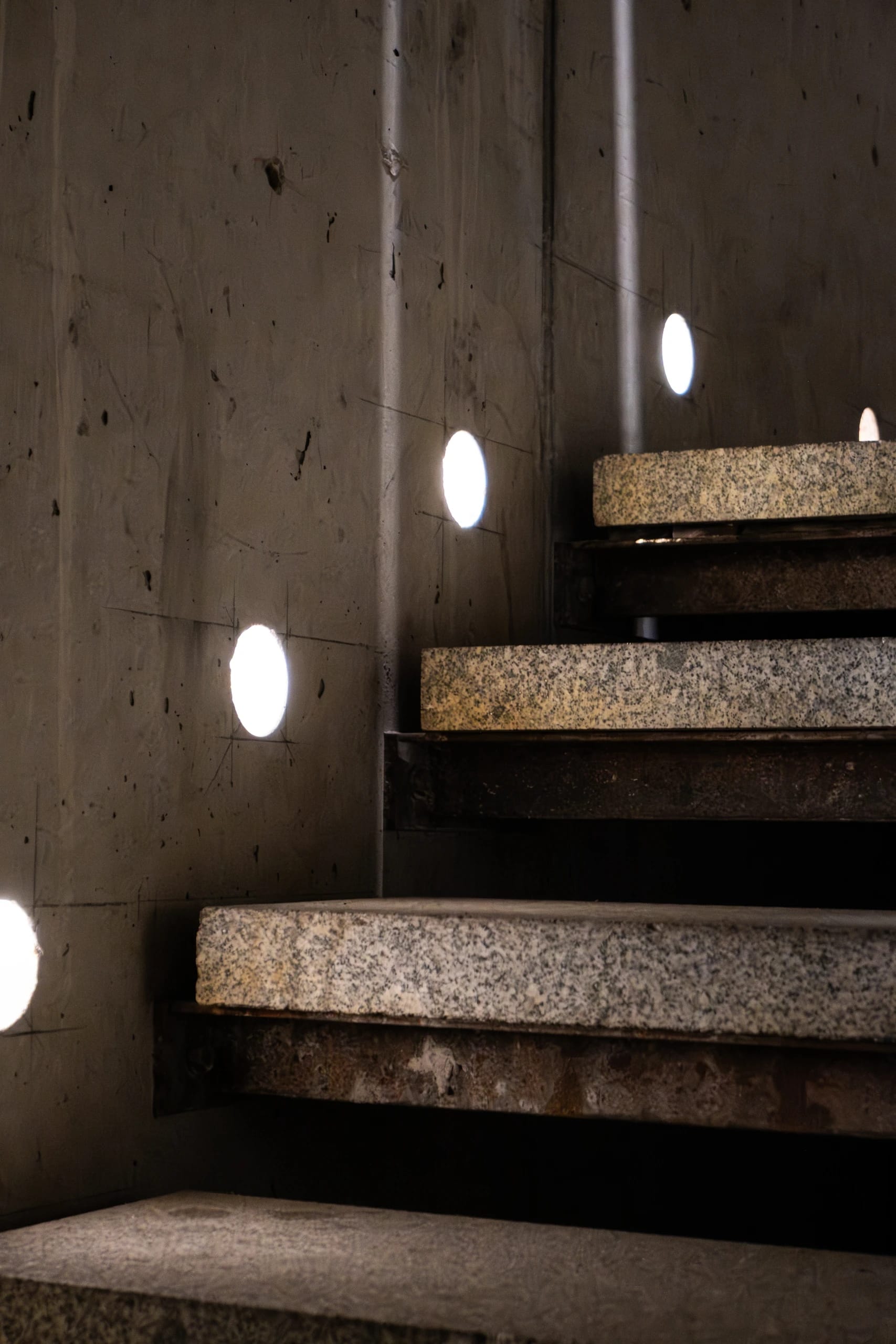 Stone steps and circular lights in a concrete stairwell