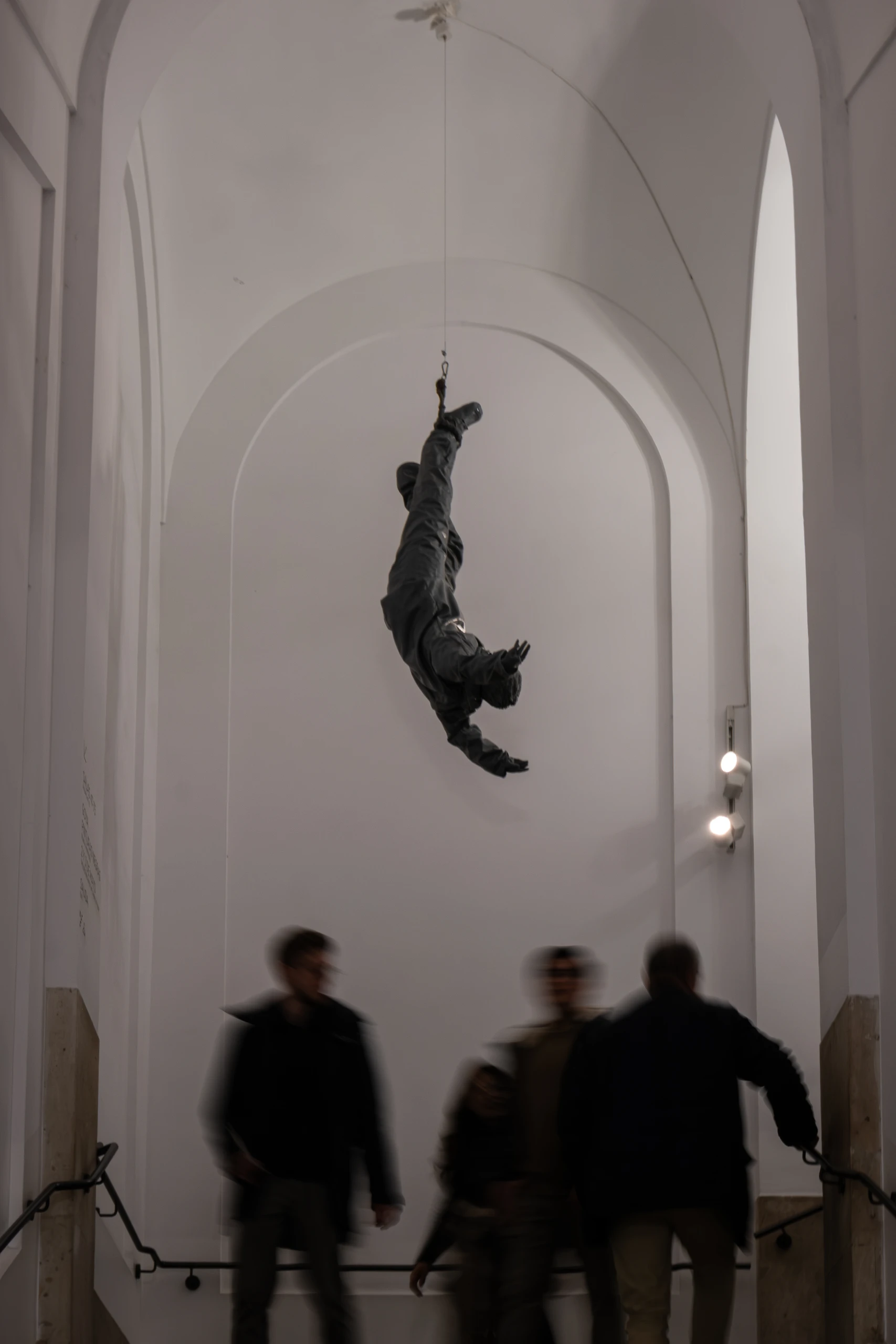 Suspended sculpture above visitors moving through a vaulted interior