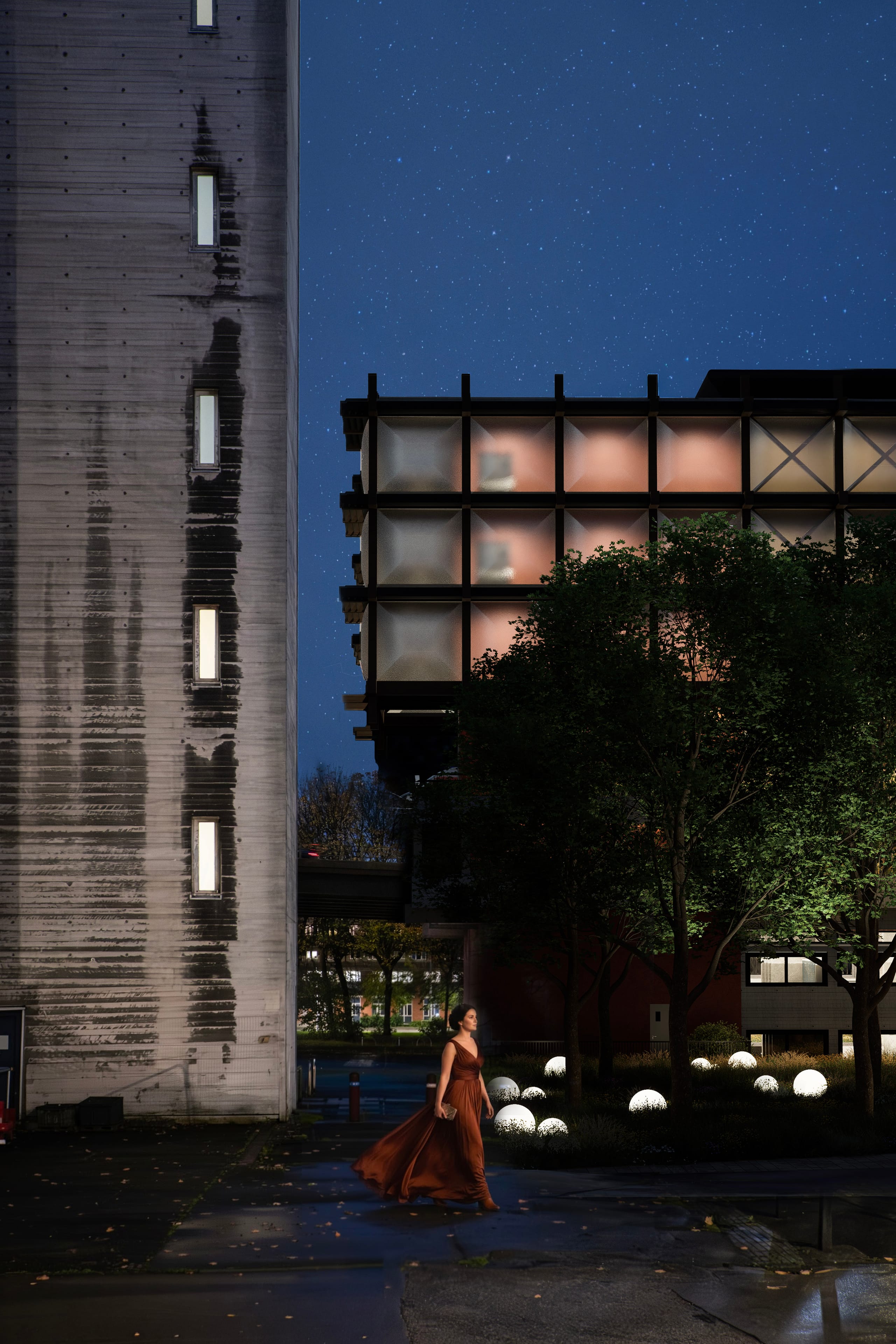 Night view of a woman in a long red dress walking past the board-marked concrete tower, with the new hall's softly glowing ETFE cushions above trees and glowing sphere lights.
