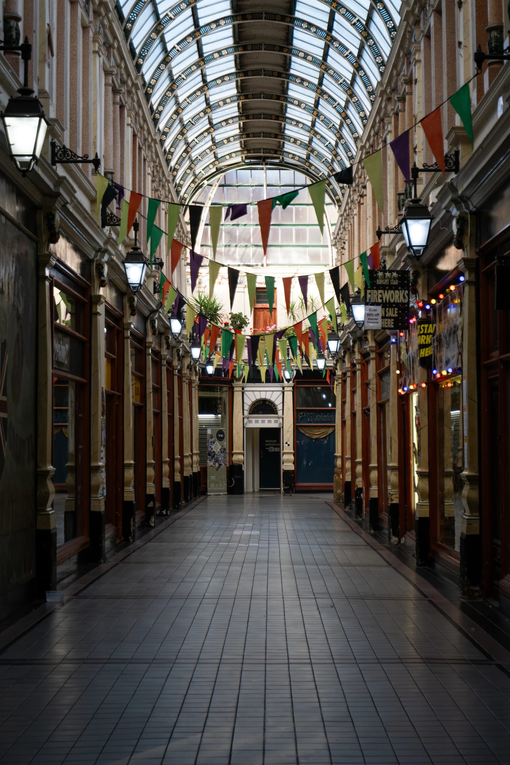 A glass-roofed shopping arcade with colourful bunting