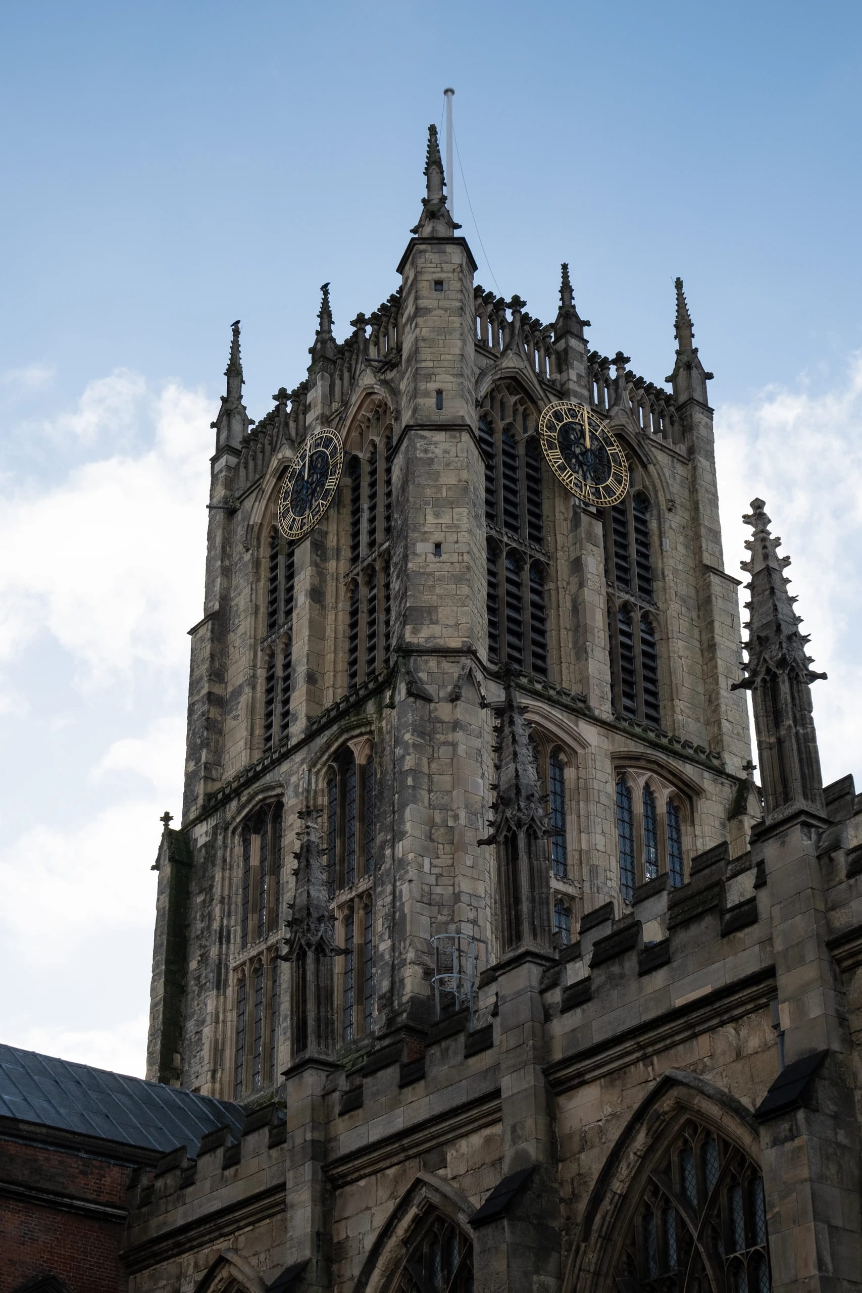 A Gothic stone clock tower beneath a cloudy sky
