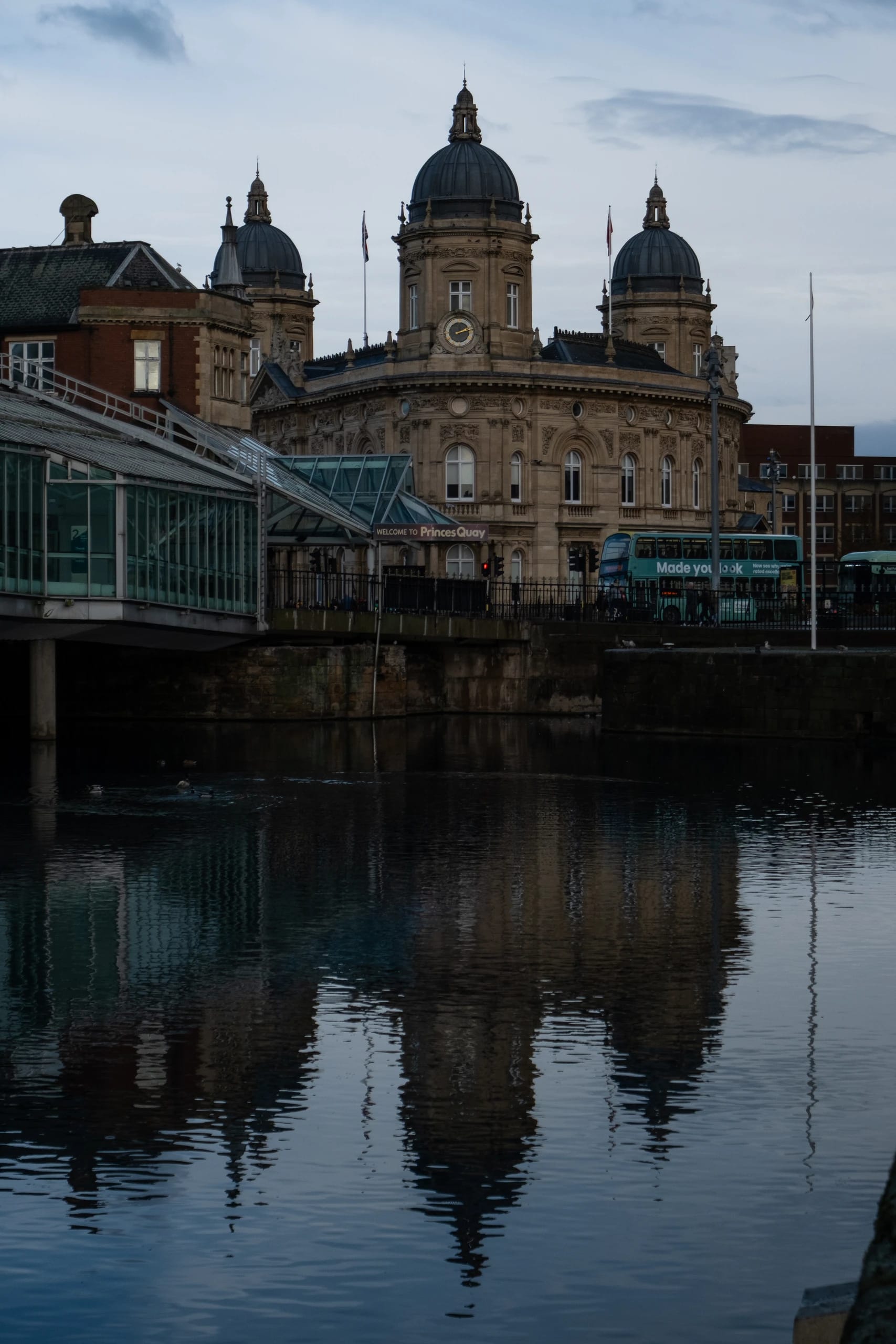 An ornate domed building reflected in the dock water