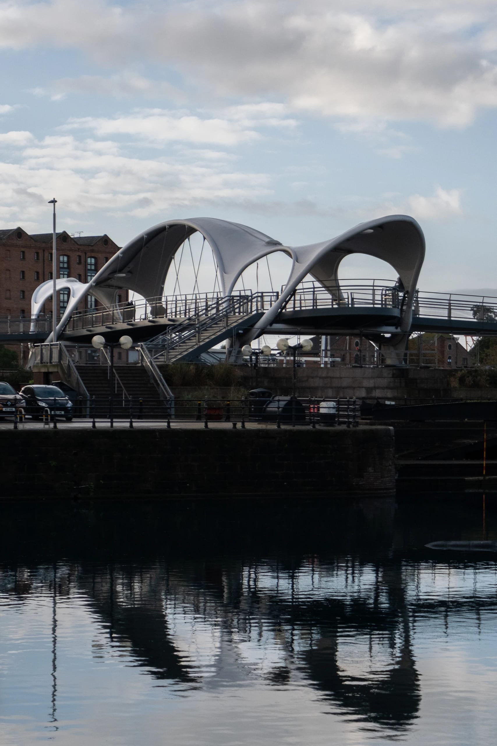 A sculptural pedestrian bridge and its reflection in the water