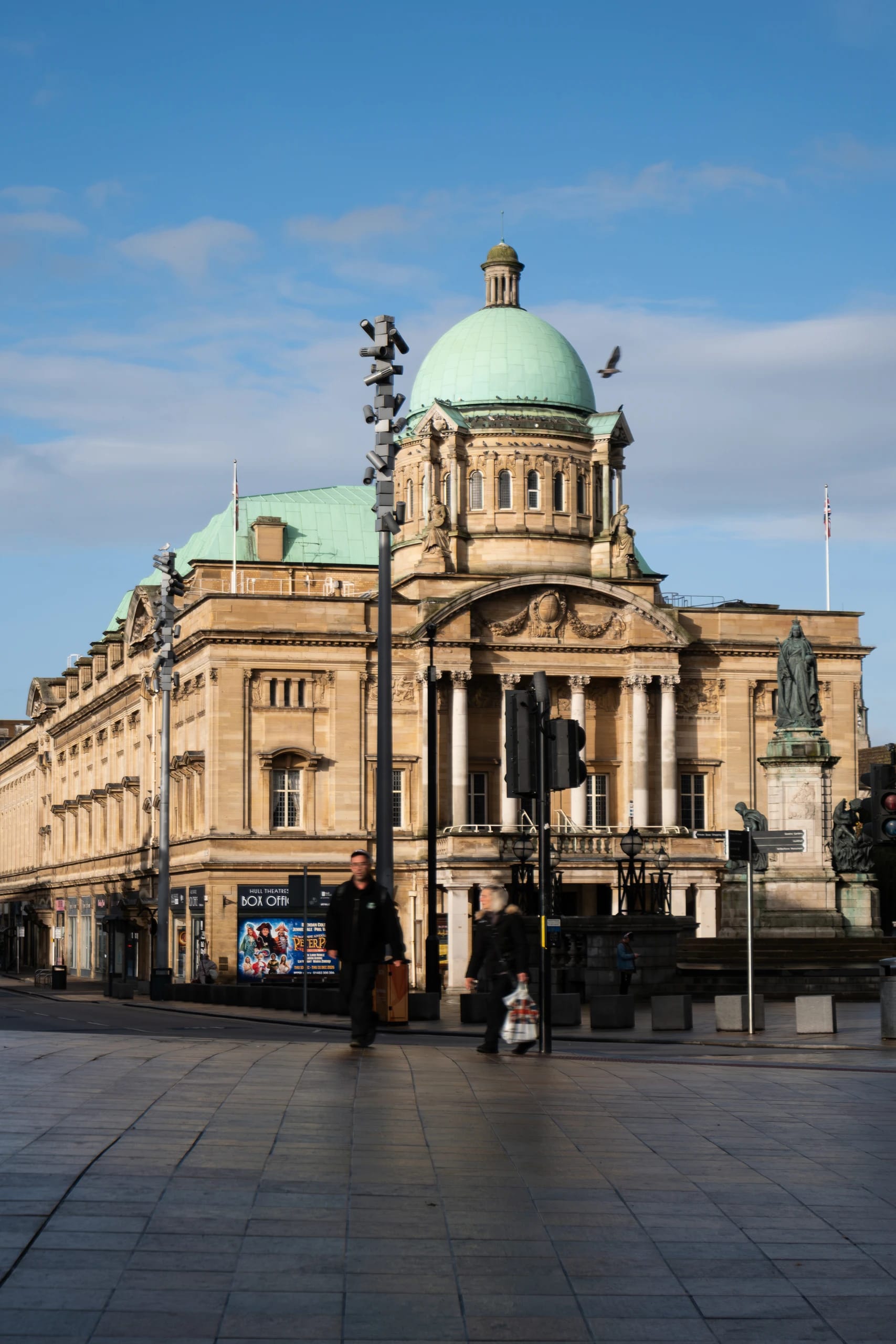 A civic building with a green dome and pedestrians in the foreground