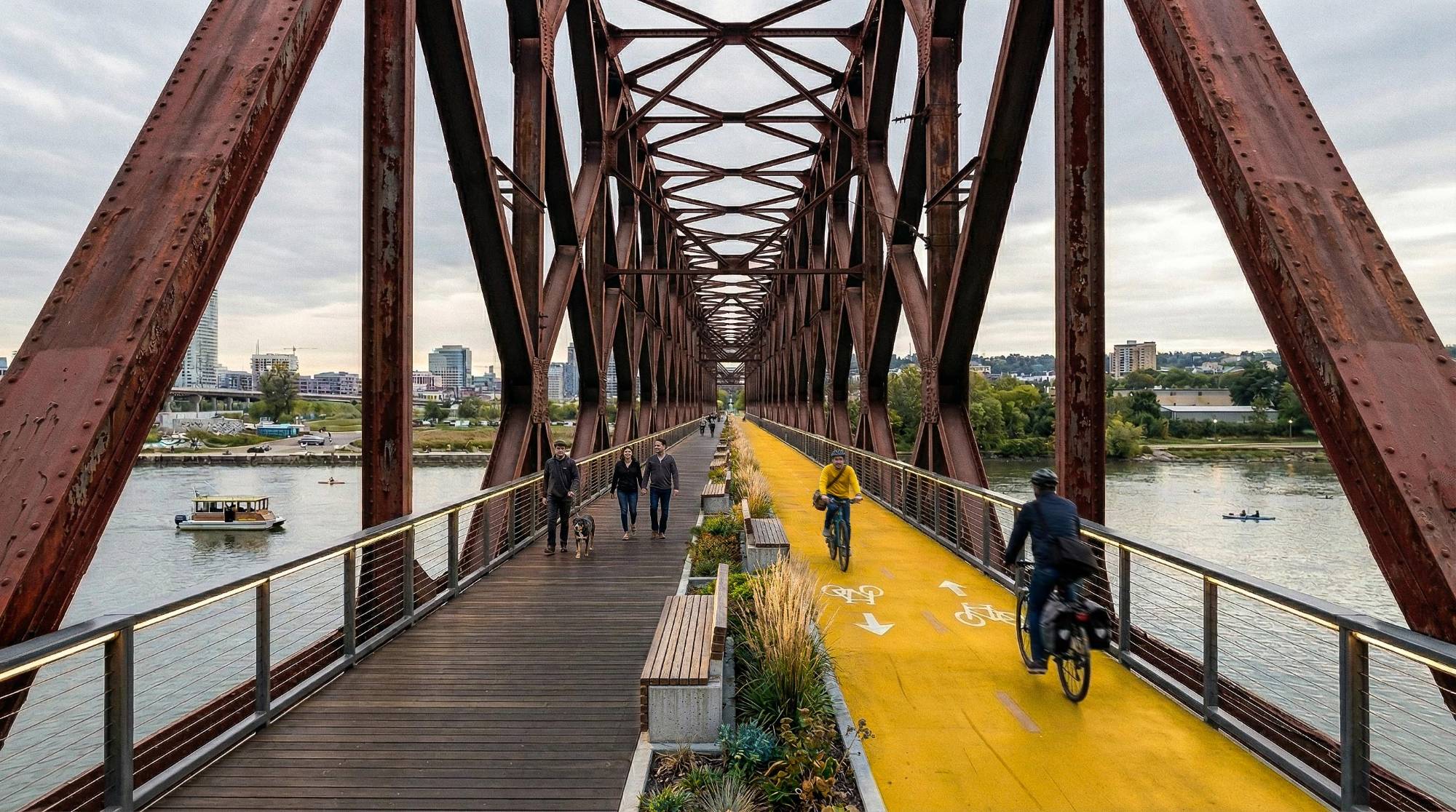 Render of the repurposed steel railway bridge with a timber walkway, planted benches and a yellow cycle lane over the river.